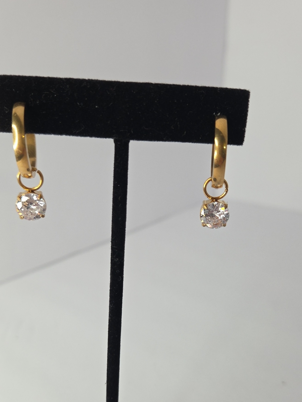 Gold-plated huggie hoop earrings featuring dangling round solitaire rhinestone